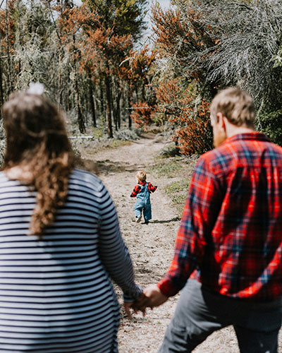 Familia en un bosque, padres de la mano hijo delante